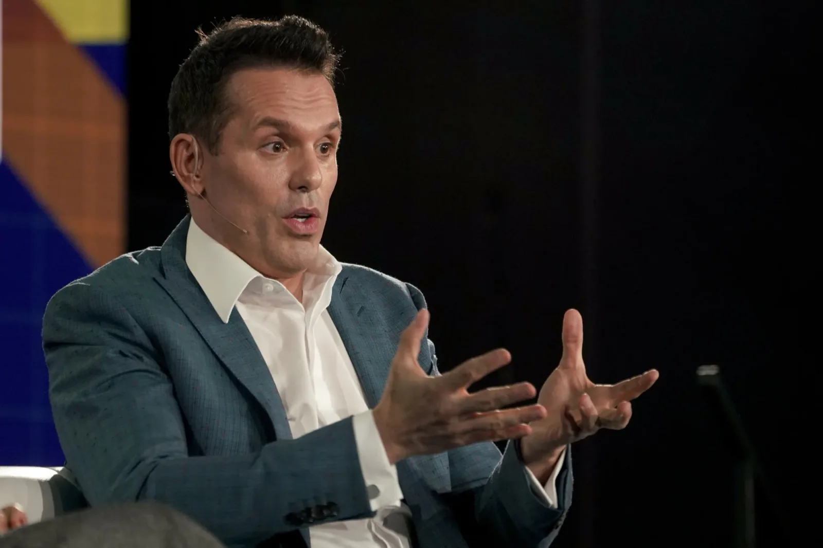 Christian Angermayer gesturing while speaking on stage at a conference