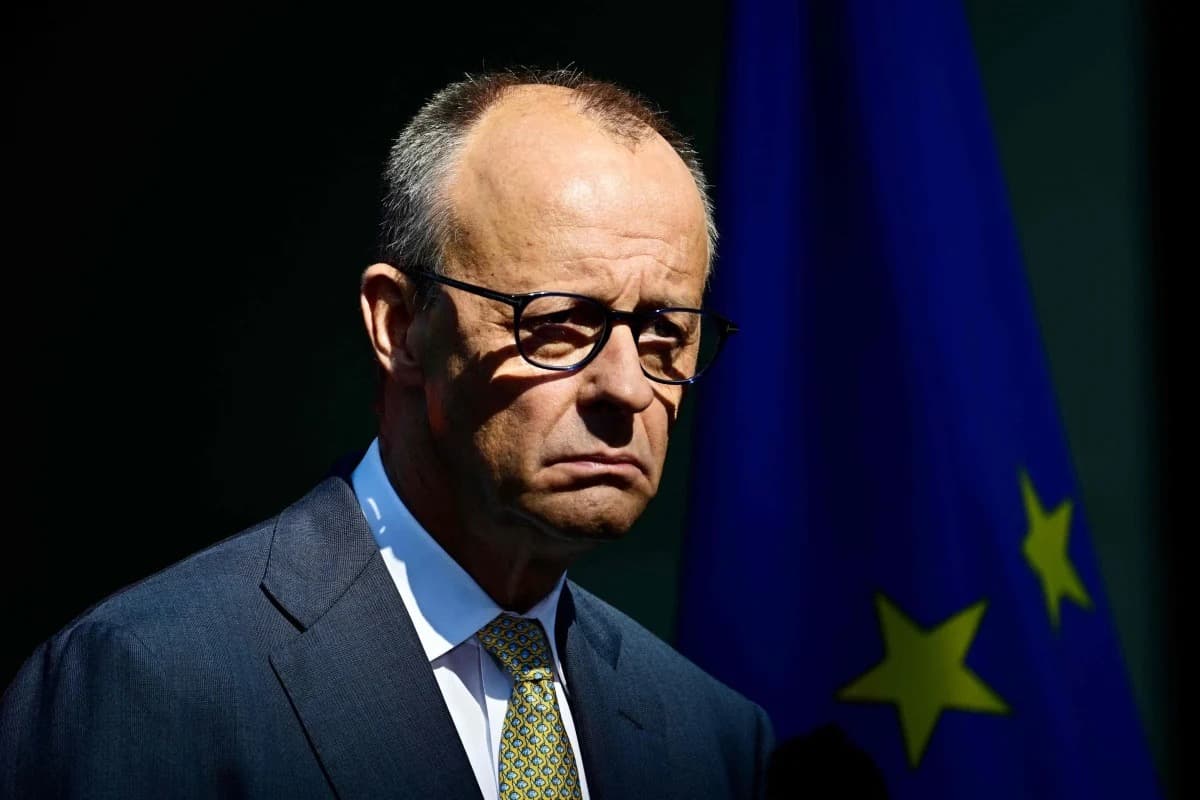 German Chancellor Friedrich Merz standing beside a European Union flag