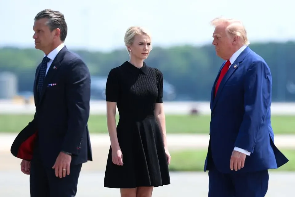 Natalie Harp standing between Pete Hegseth and Donald Trump on an airport tarmac