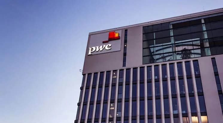 The PwC logo on an office building at dusk