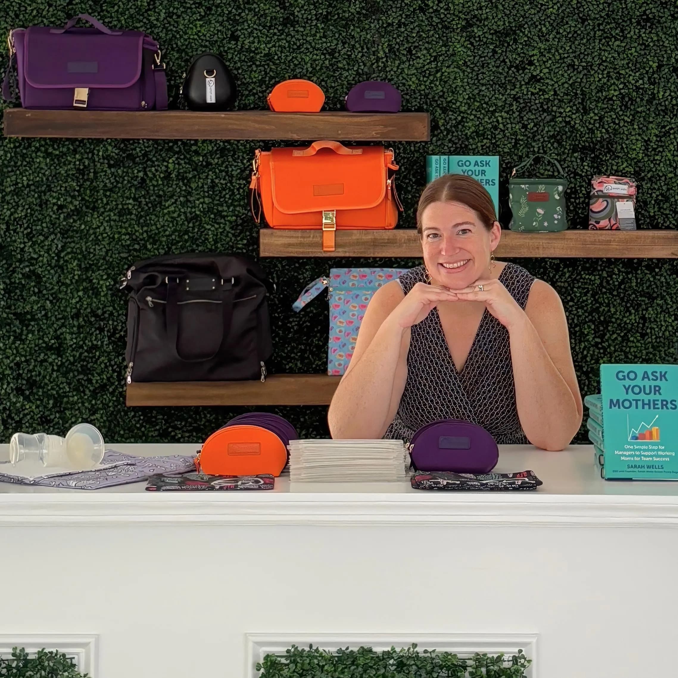 Sarah Wells behind a counter displaying her line of bags for nursing mothers
