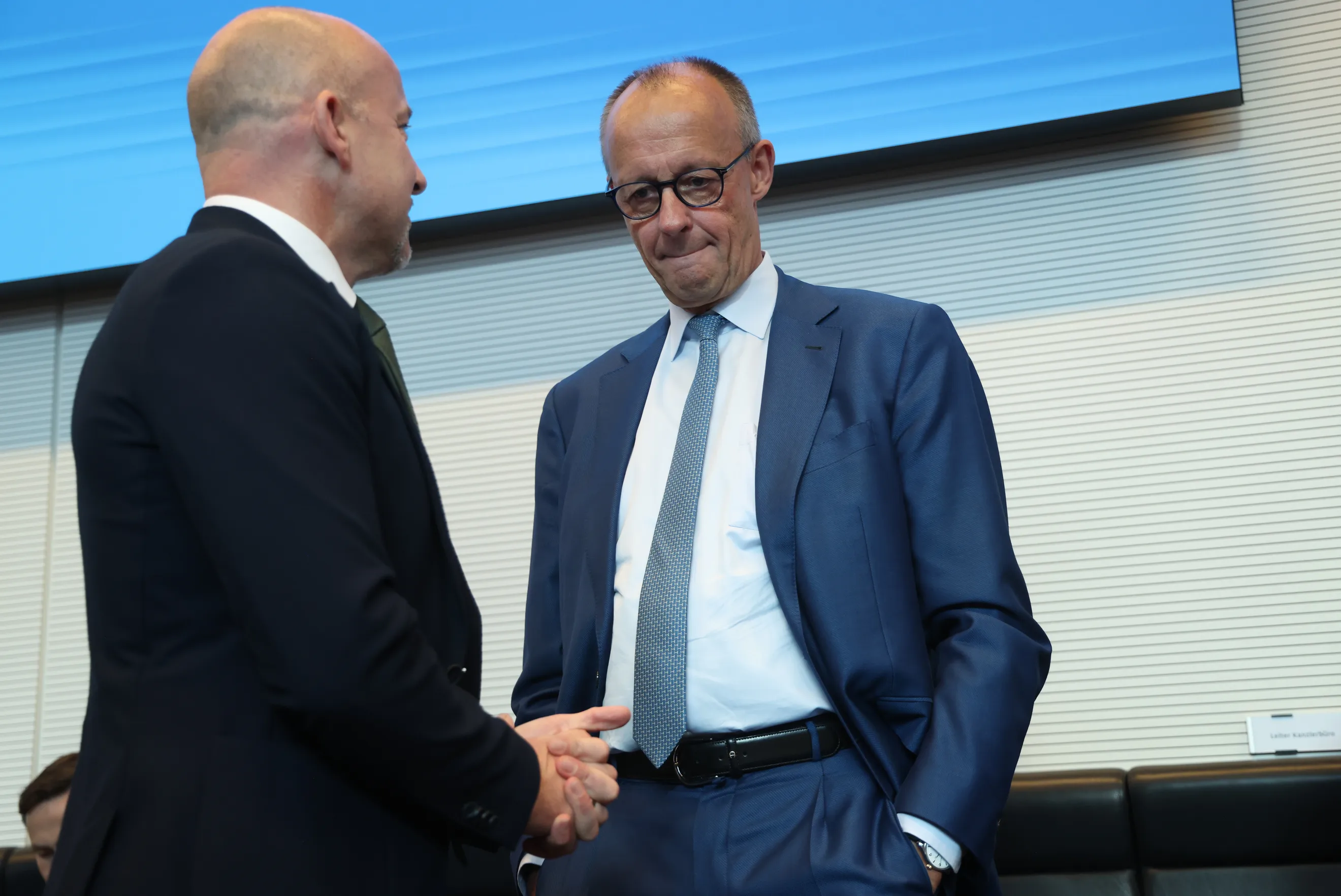 German Chancellor Friedrich Merz, right, greets a colleague at an event
