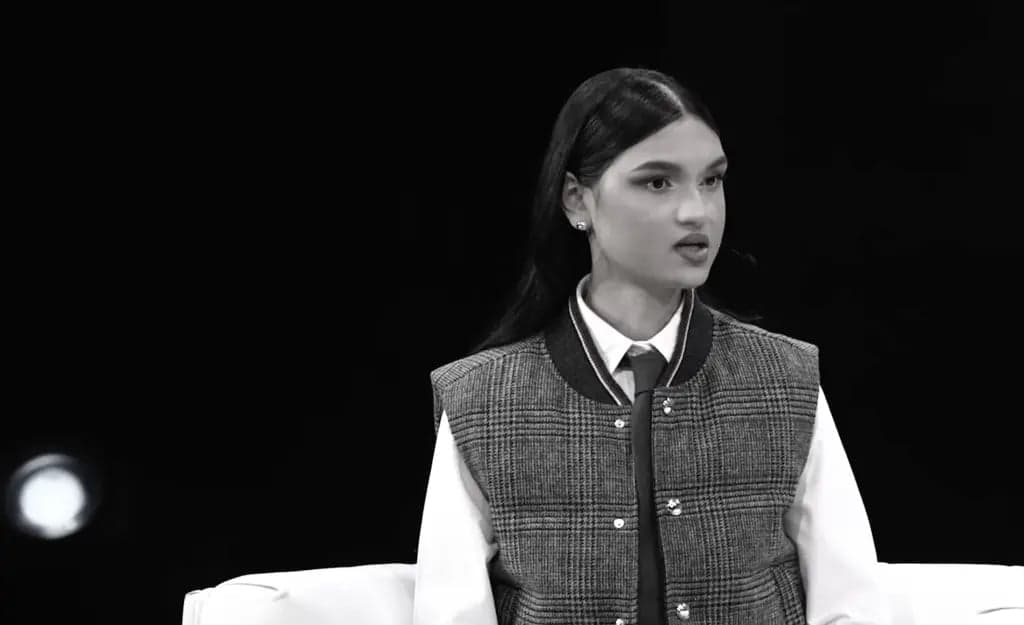 A young woman with a lapel microphone speaking on stage in a black and white photo