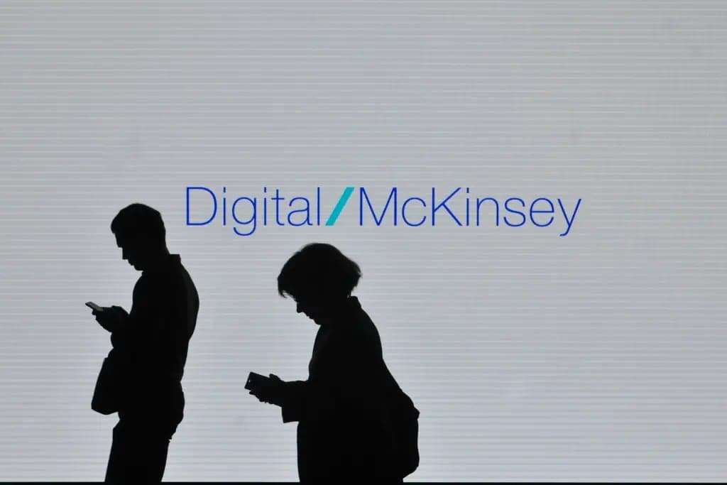 Silhouettes of two people looking down at their phones in front of a large Digital McKinsey sign